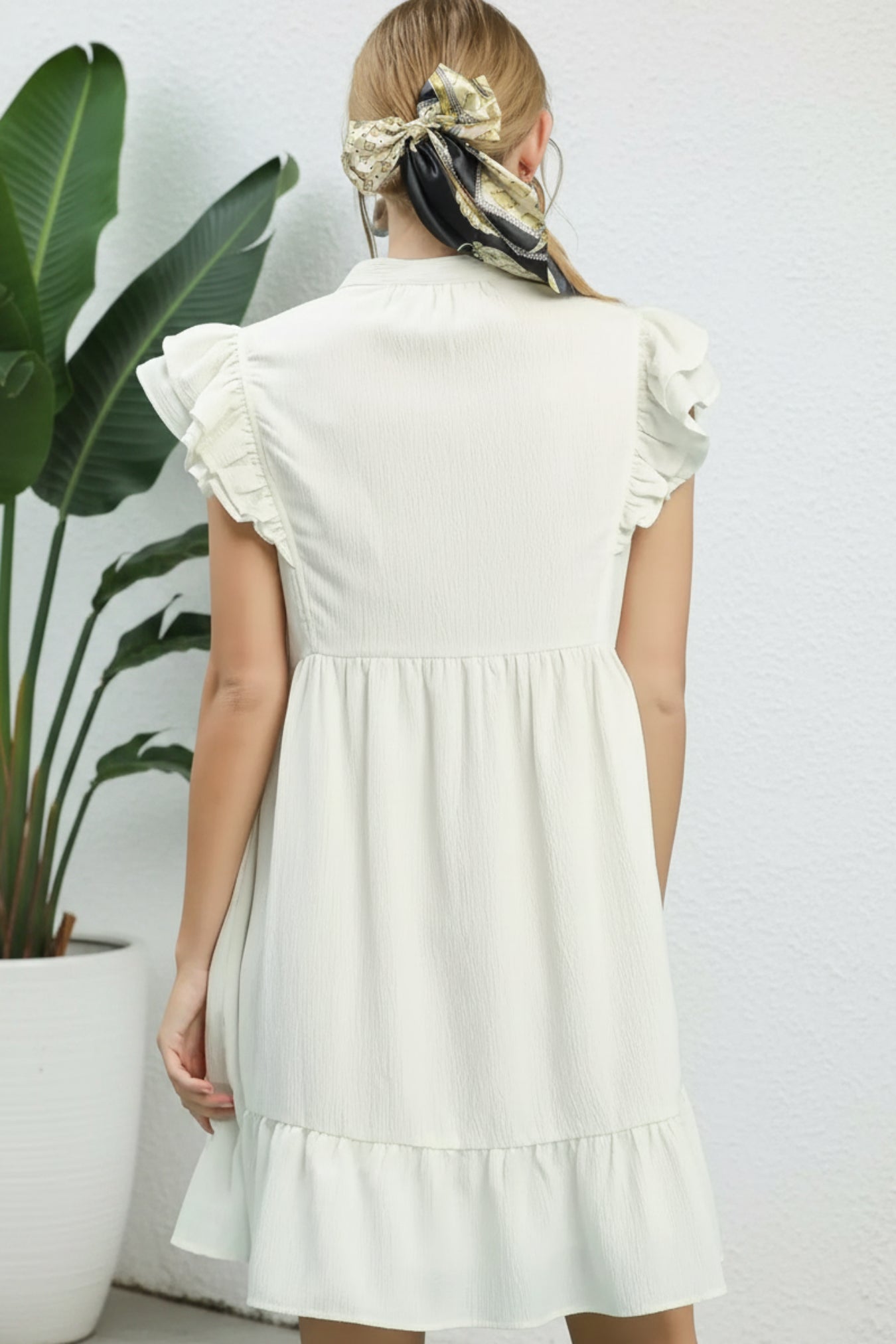 White dress with ruffled sleeves and bottom on a light blue background