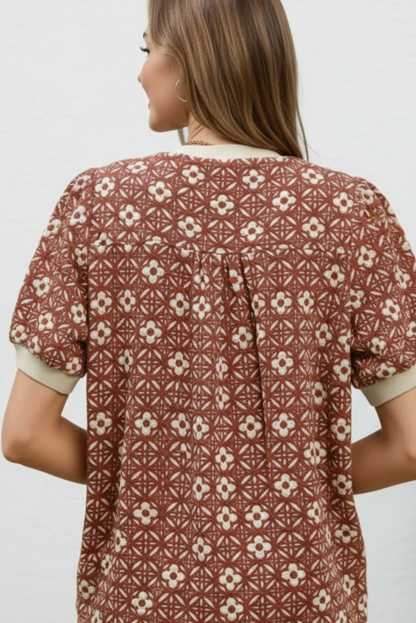 Woman wearing a patterned shirt with geometric and floral design on a white background