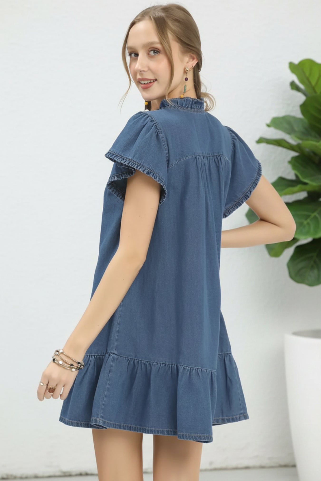Woman wearing a light denim dress on a white background