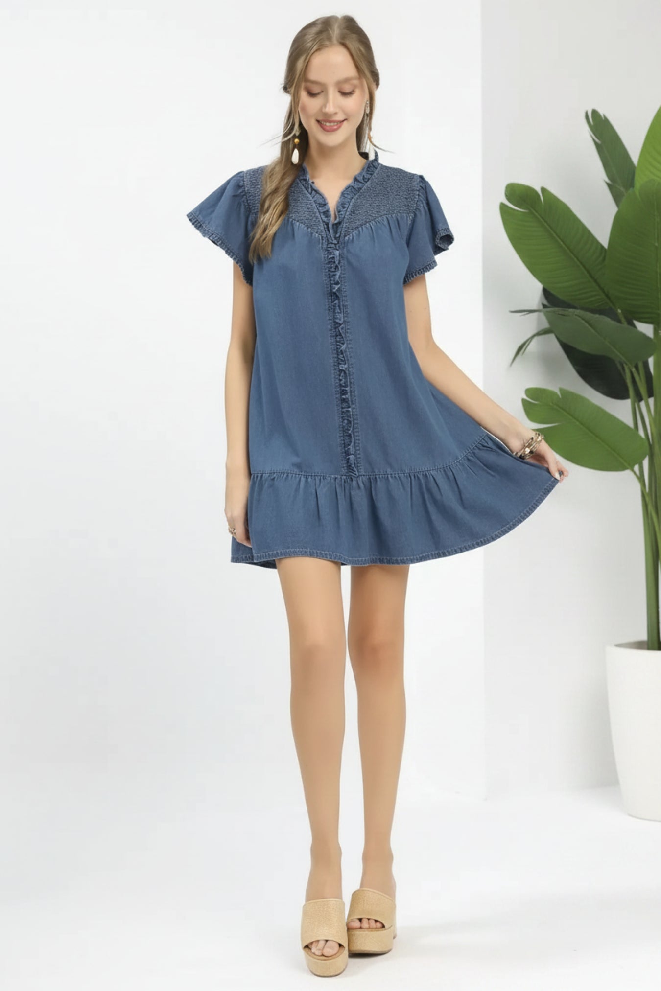 Woman wearing a light denim dress on a white background