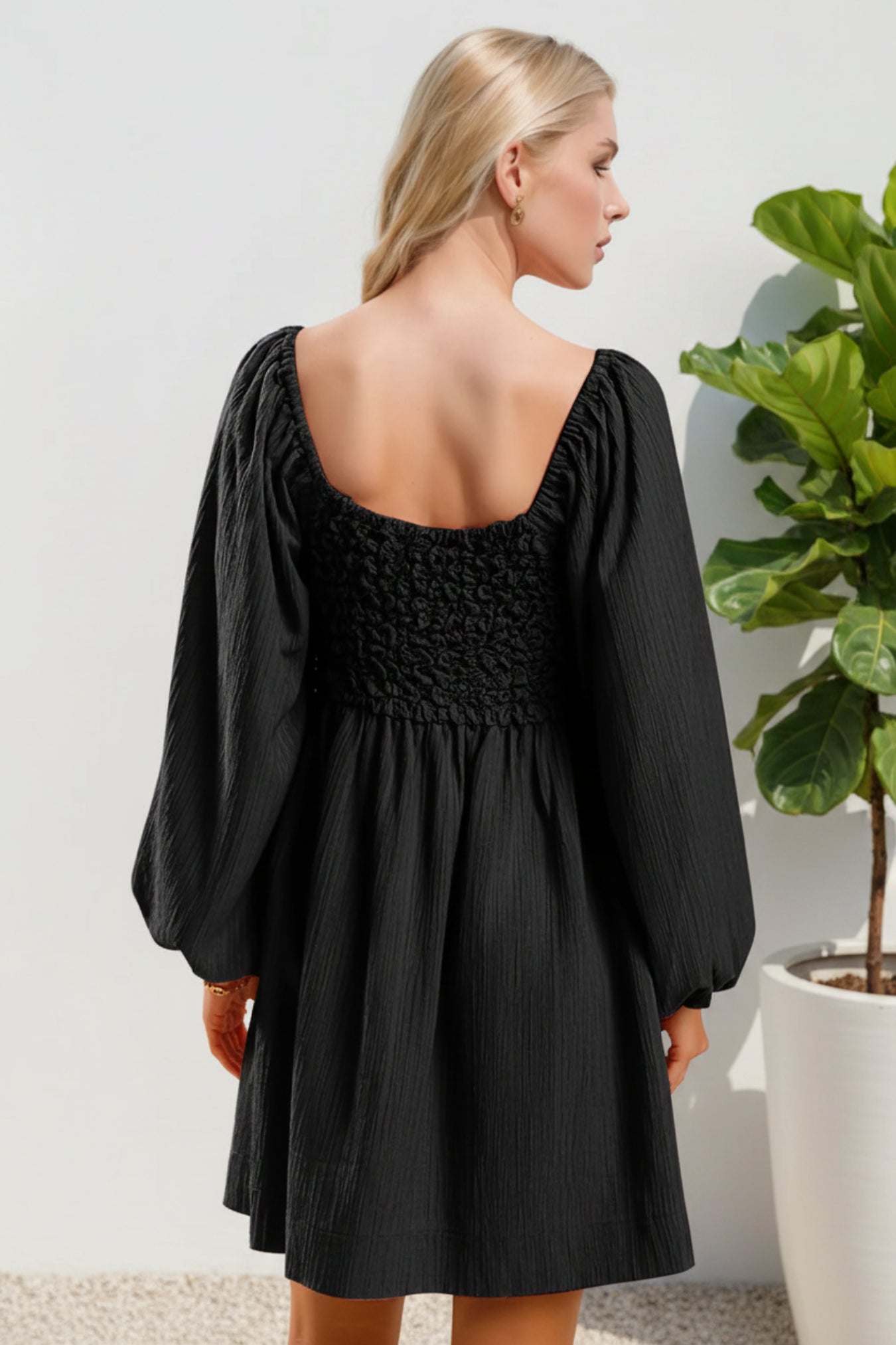 Woman wearing a black dress with long sleeves against a light background