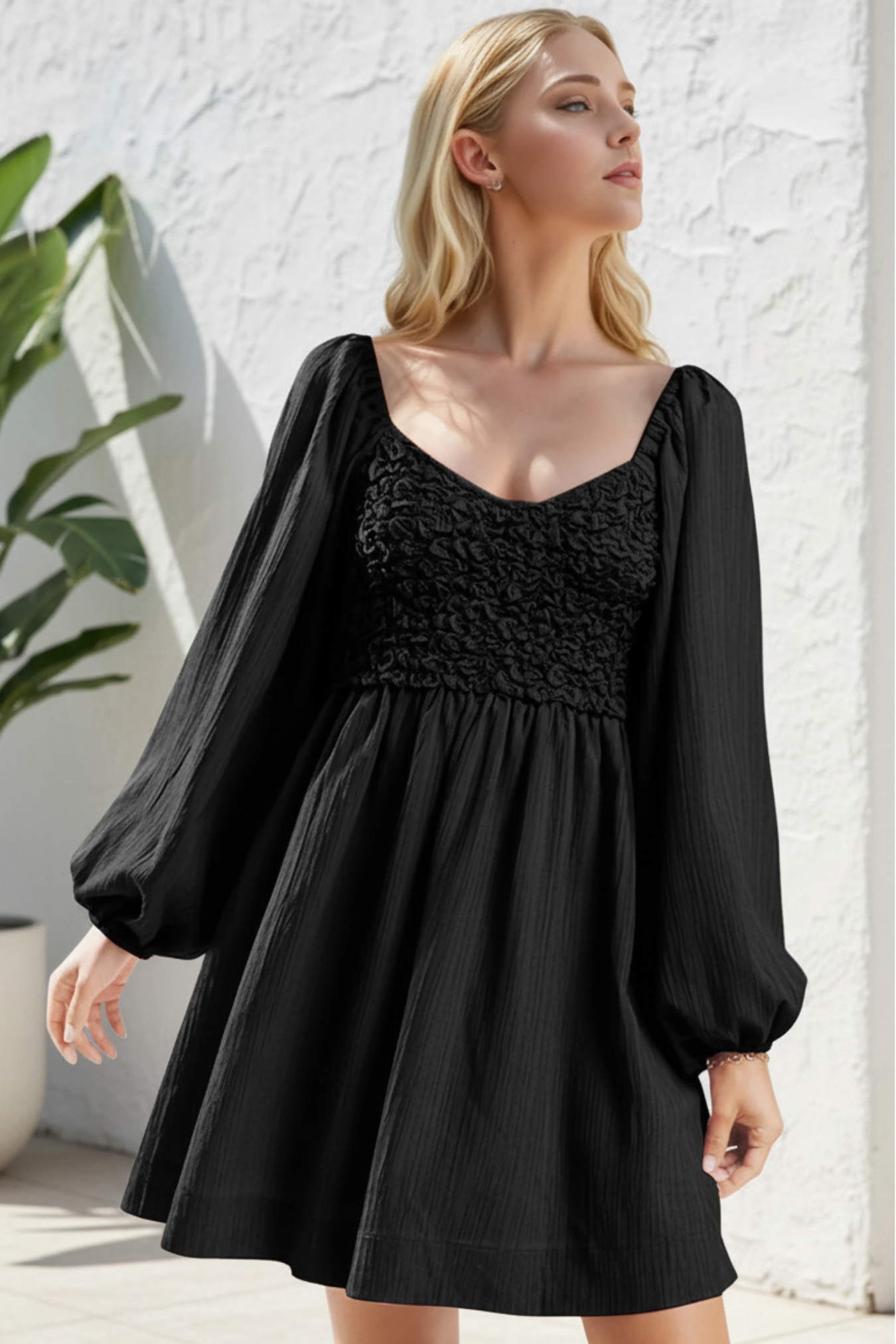 Woman wearing a black dress with puffed sleeves against a neutral background