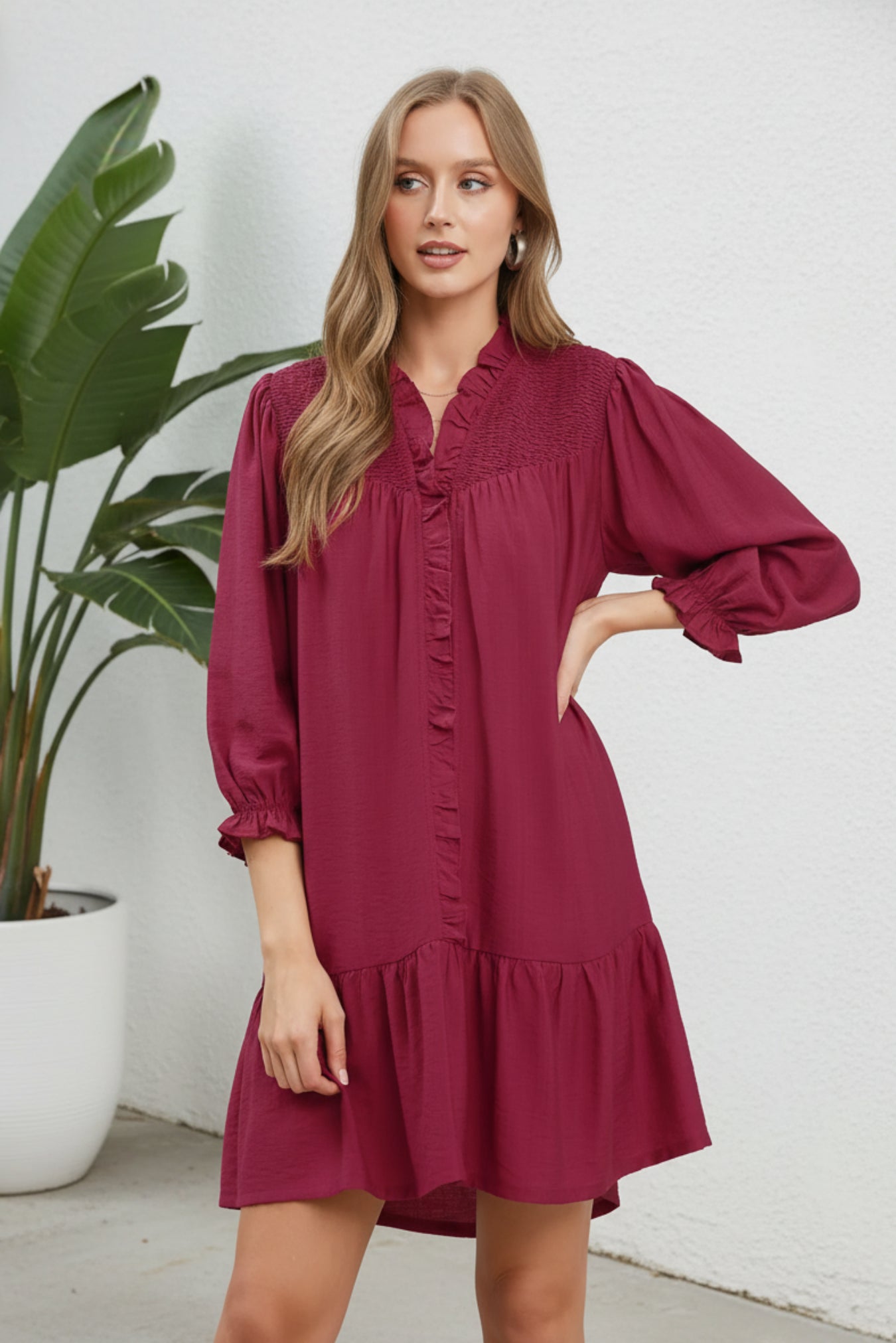 Woman wearing a burgundy dress with long sleeves on a white background