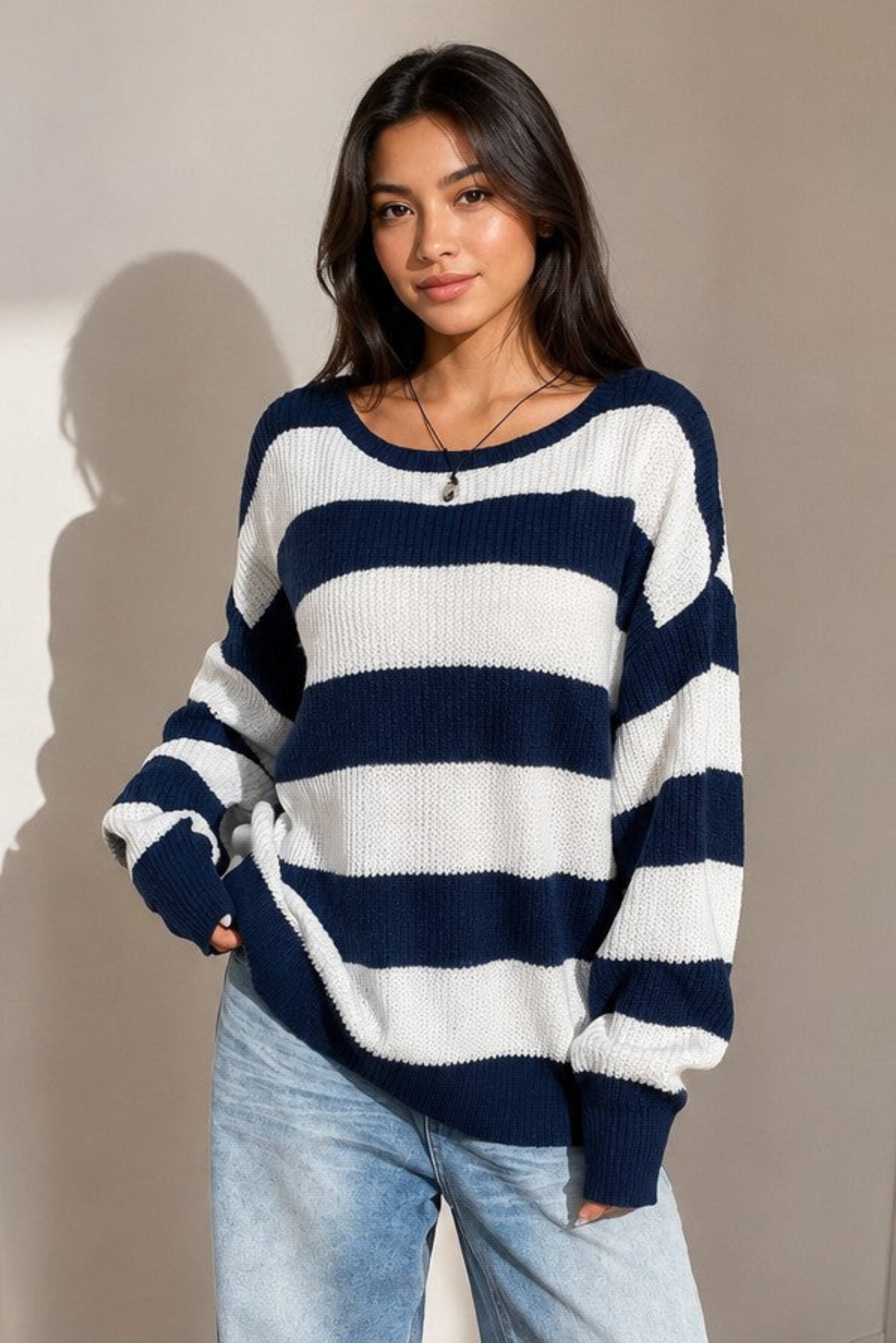 A woman stands in a gym wearing high-waisted gray capri leggings, a white crossover sports bra, and white sneakers.
