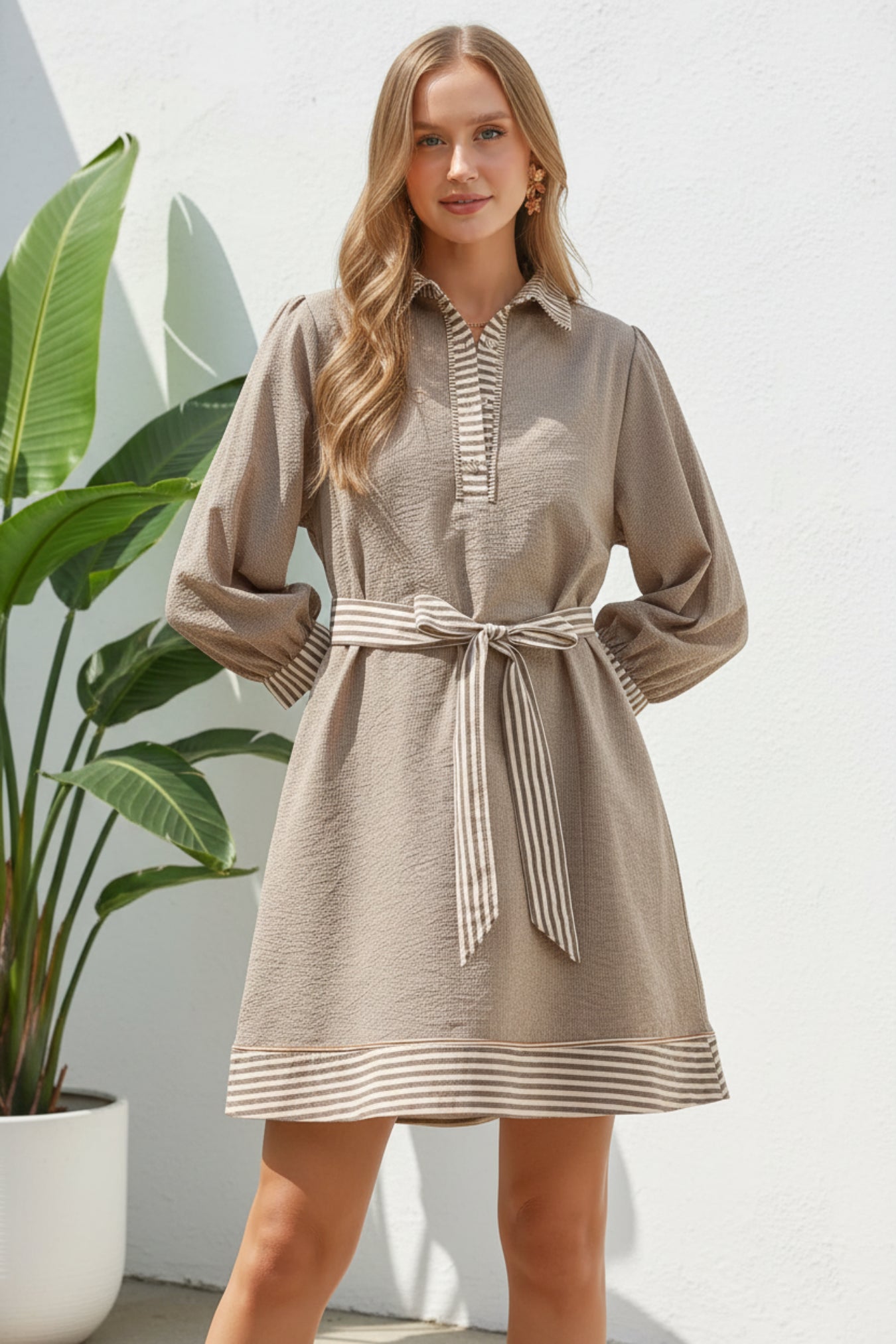 Woman wearing a brown dress with striped details on a white background