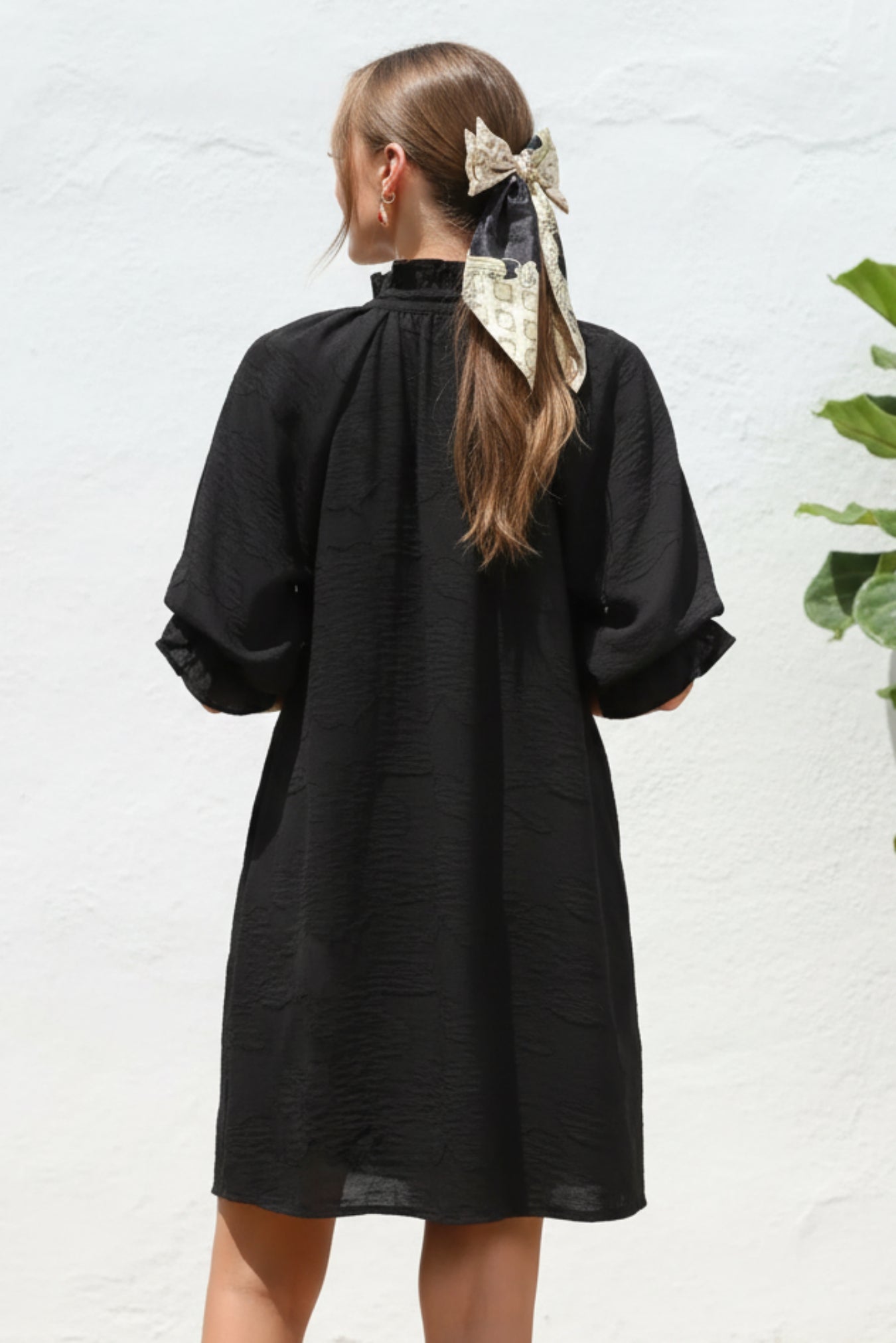 Person wearing a black dress against a white background