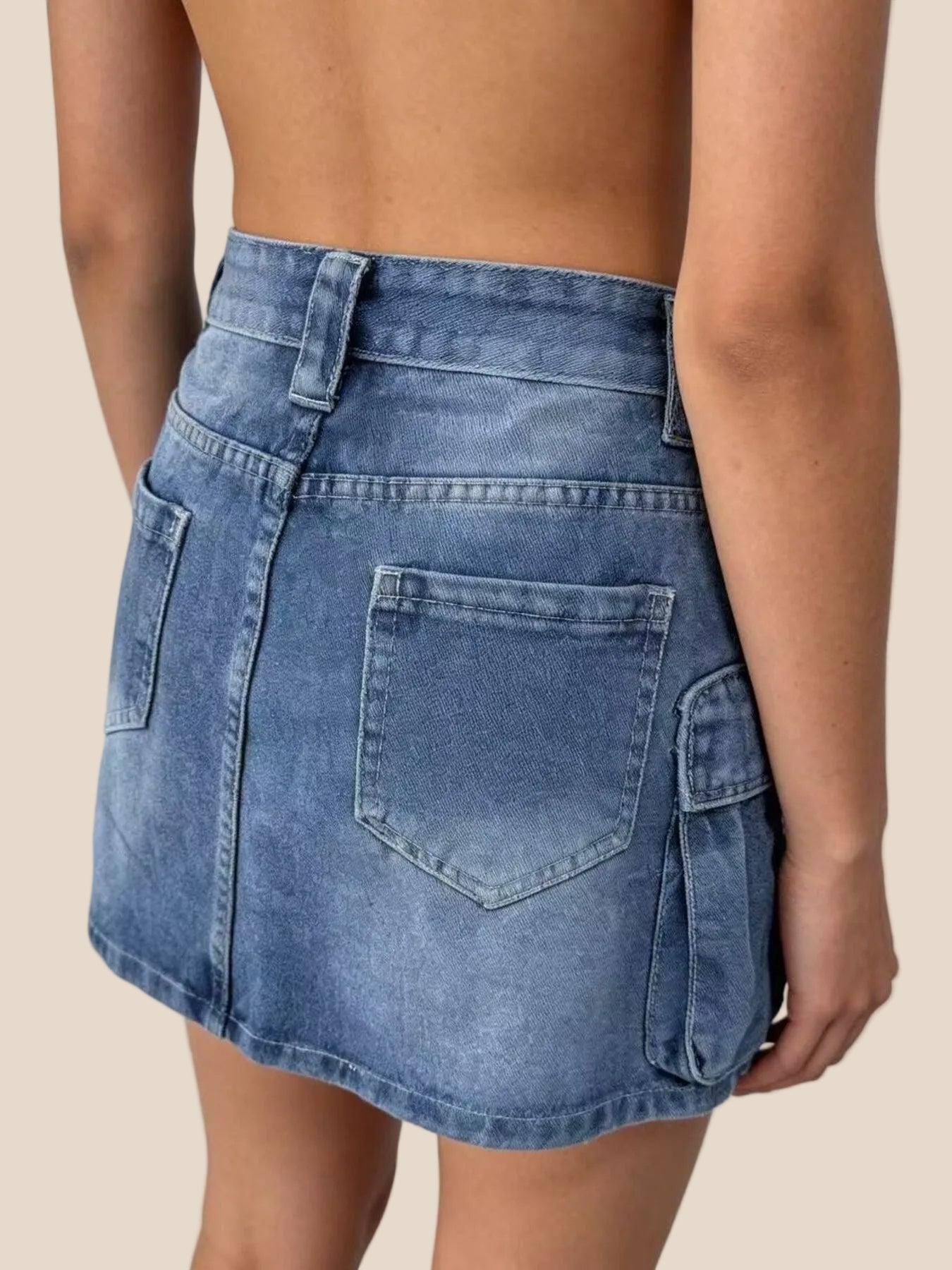 Blue denim skirt worn by a person on a white background