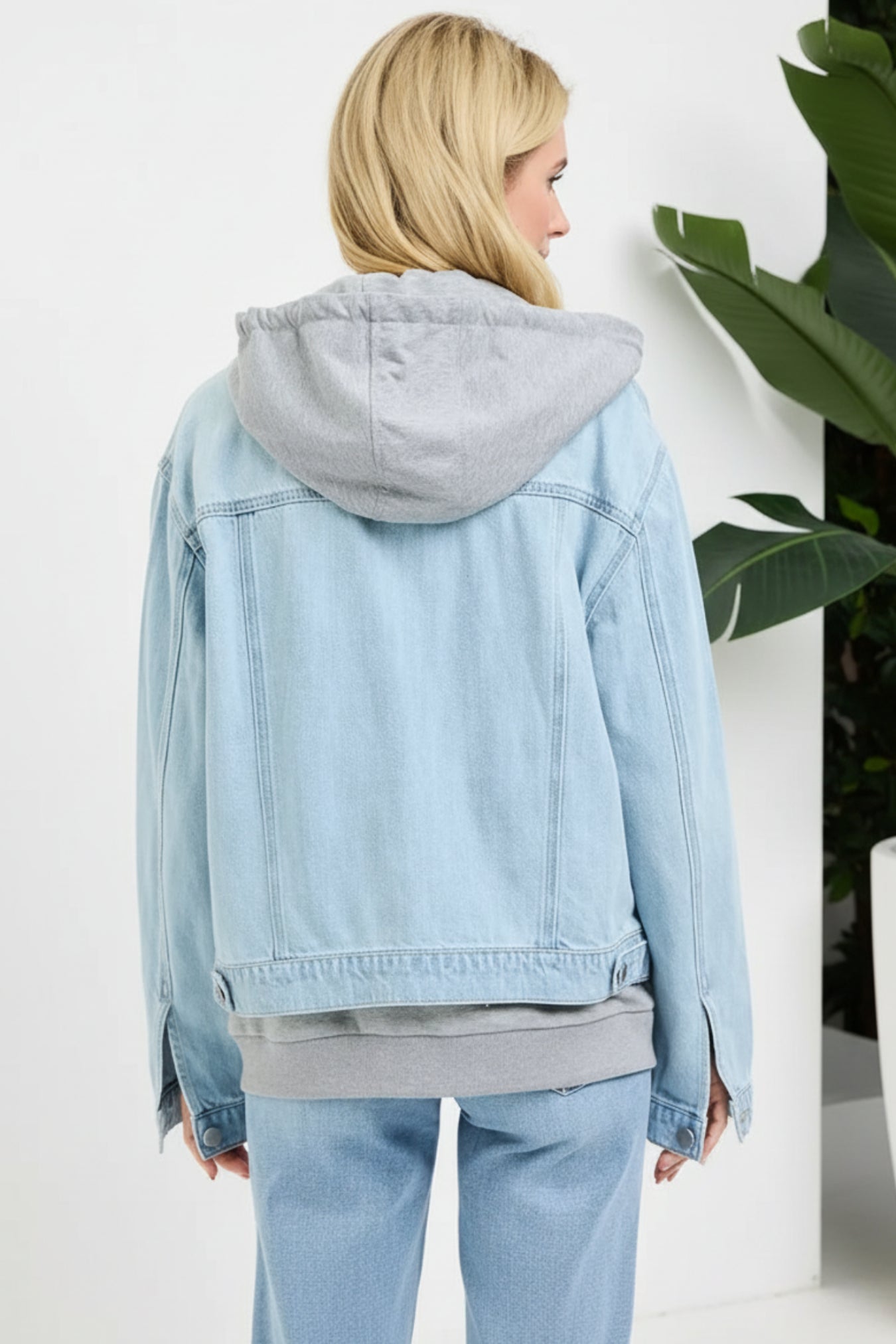 Light blue denim jacket with gray hood worn by a person on a white background