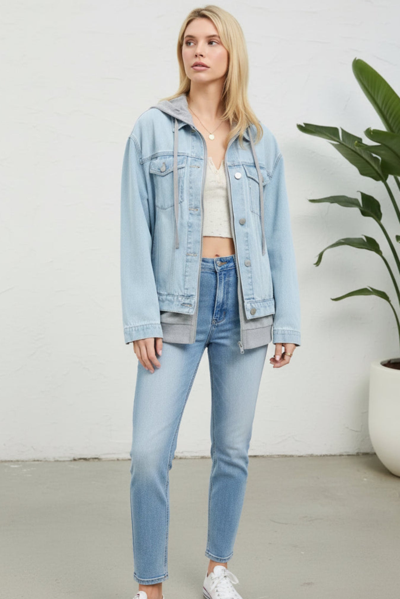Woman wearing a light blue denim jacket with a gray hood on a white background